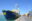 Humanity 1 in den SOS Humanity-Farben gelb und blau im Hafen von Siracusa mit blauem Himmel und der Stadt im Hintergrund.