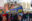 Foto einer Demonstration in Berlin mit vielen Menschen und einem großen, blau-gelben Banner mit der Aufschrift "Leben retten ist Pflicht" von SOS Humanity.