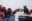 Rettungssituation mit einem Crewmitglied von SOS Humantiy, das Flüchtlingen auf einem Boot Rettungswesten reicht.