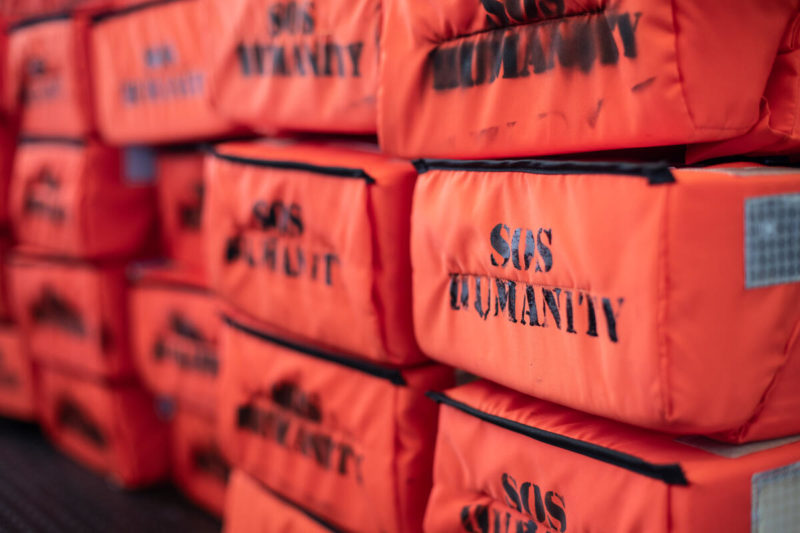 Gestapelte Rettungswesten mit Aufdruck SOS Humanity