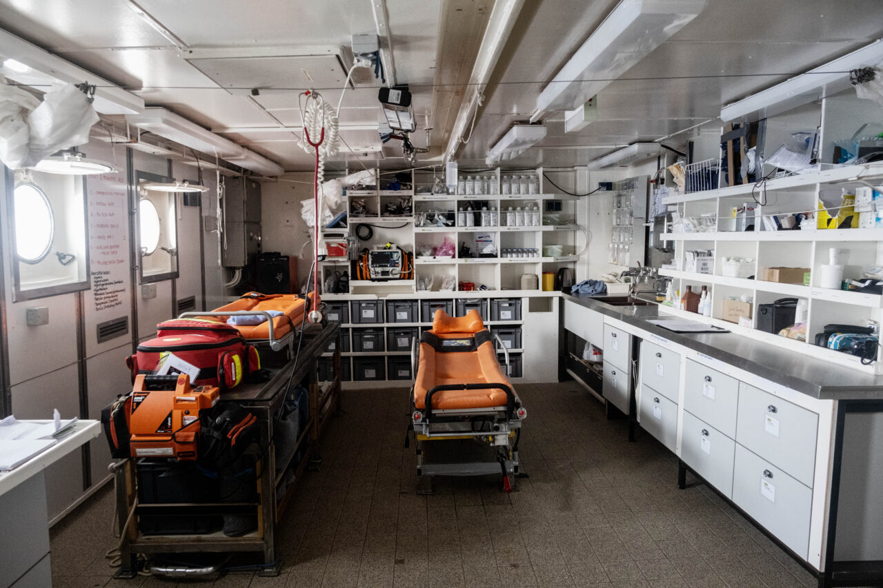 Notfallklinik an Bord der Humanity 1 mit orangen Liegen und weißen Medikamentenschränken.