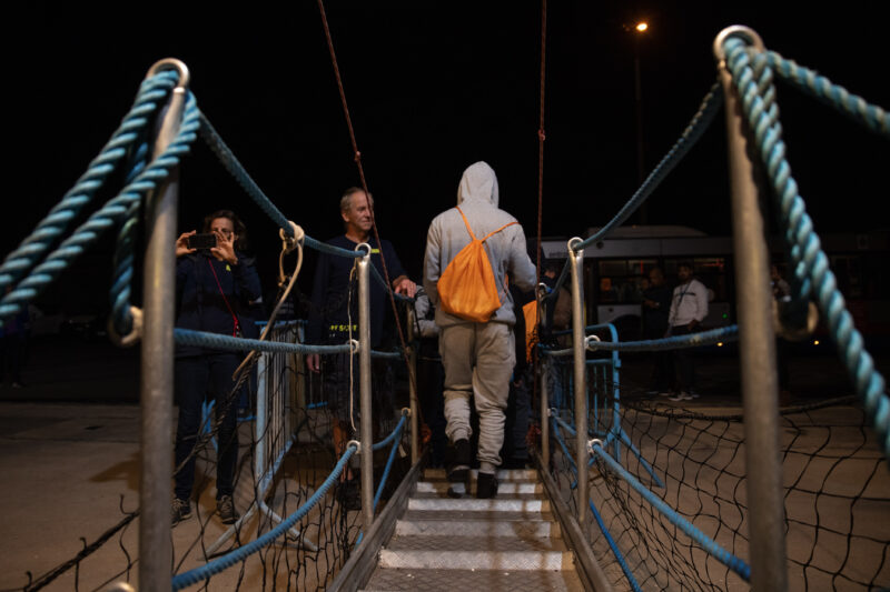 Ausschiffung nachts: Geretteter mit orangem Rucksack geht von der Humanity 1 an Land.