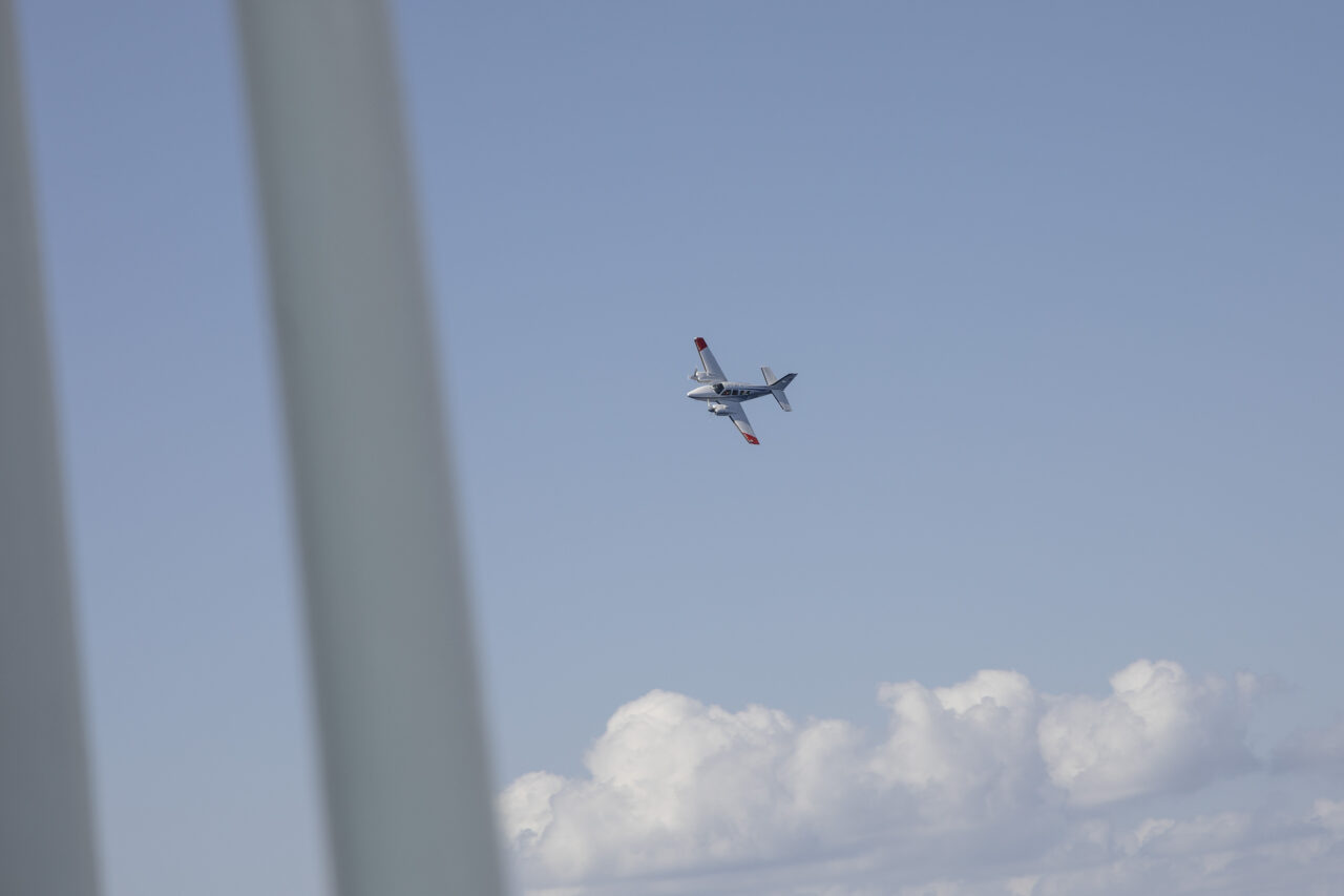 Flugzeug vor blauem Himmel mit weißer Wolke im unteren Teil des Fotos.