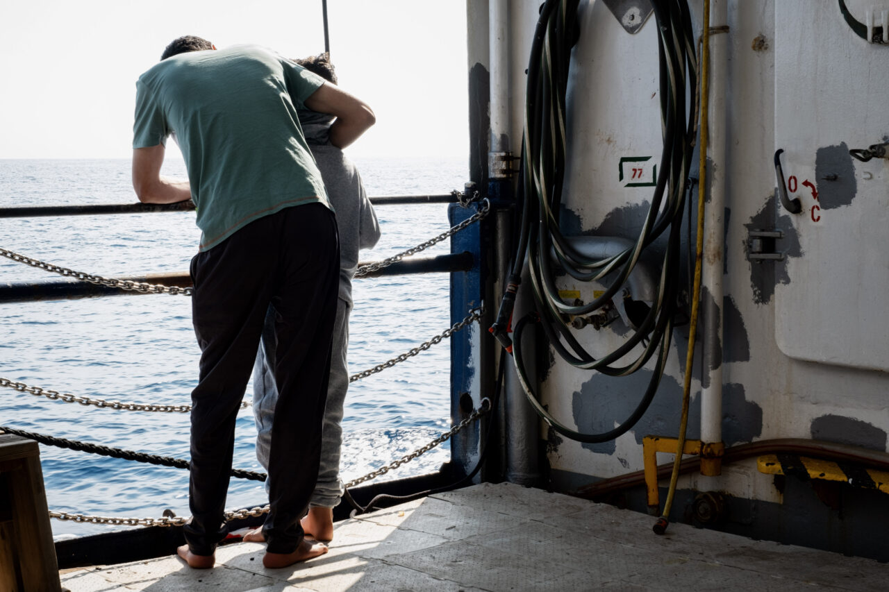 Zwei Gerettete an Bord der Humanity 1 blicken auf das Wasser des Mittelmeers.