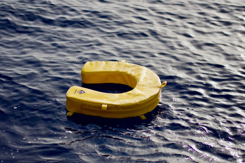 Gelber Rettungsring auf blauem Wasser.