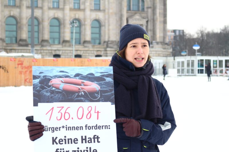 Marie von SOS Humanity hält ein Plakat mit der Unterschriftenanzahl der Petition "Keine Haft für Seenotrettung" vor dem Bundestag