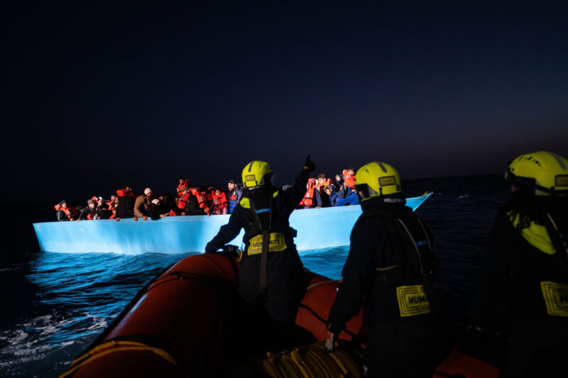 Blaues Boot mit Menschen mit Rettungswesten und davor ein Rettungsschlauchboot mit Crewmitgliedern der Humanity 1.