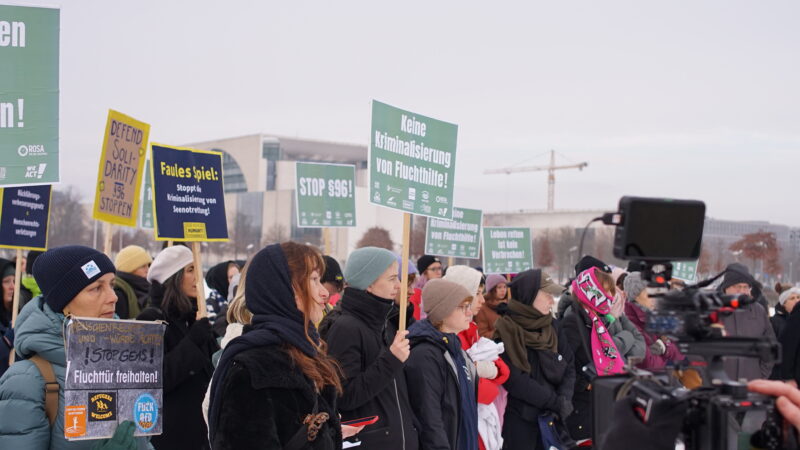 Demonstrant*innen vor dem Bundestag mit blauen Schildern.