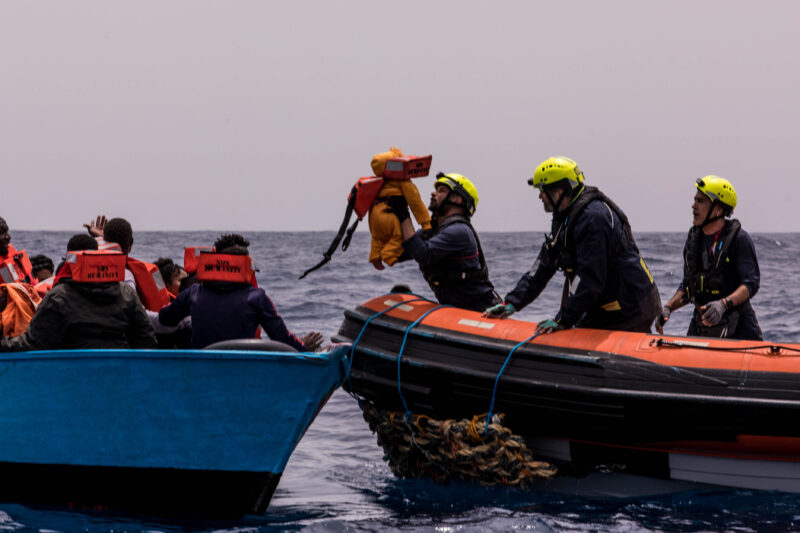 Crewmitglieder von SOS Humanity helfen einem Baby an Bord des RHIBs.
