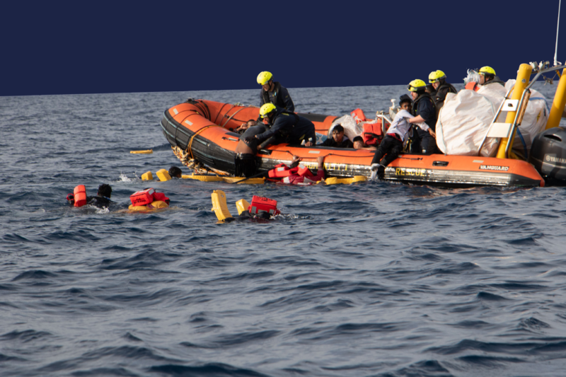 Foto eines RHIBs von SOS Humanity und mehreren Menschen mit Rettungswesten im Wasser