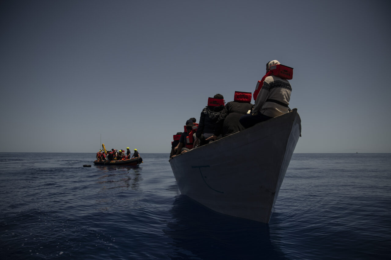 Boot mit Flüchtenden im Vordergrund, RHIB im Hintergrund