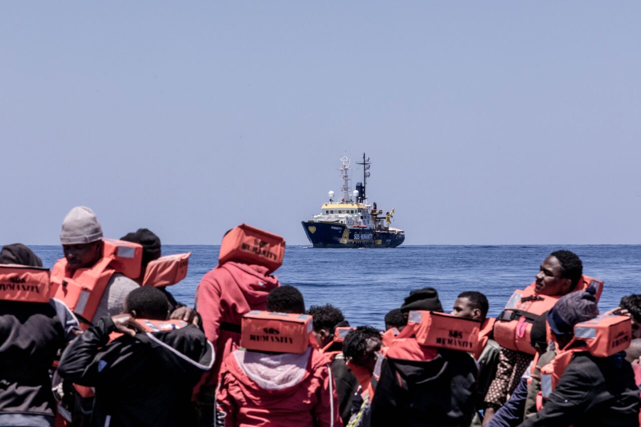 Flüchtende mit Rettungswesten von hinten, Humanity am Horizont zu sehen