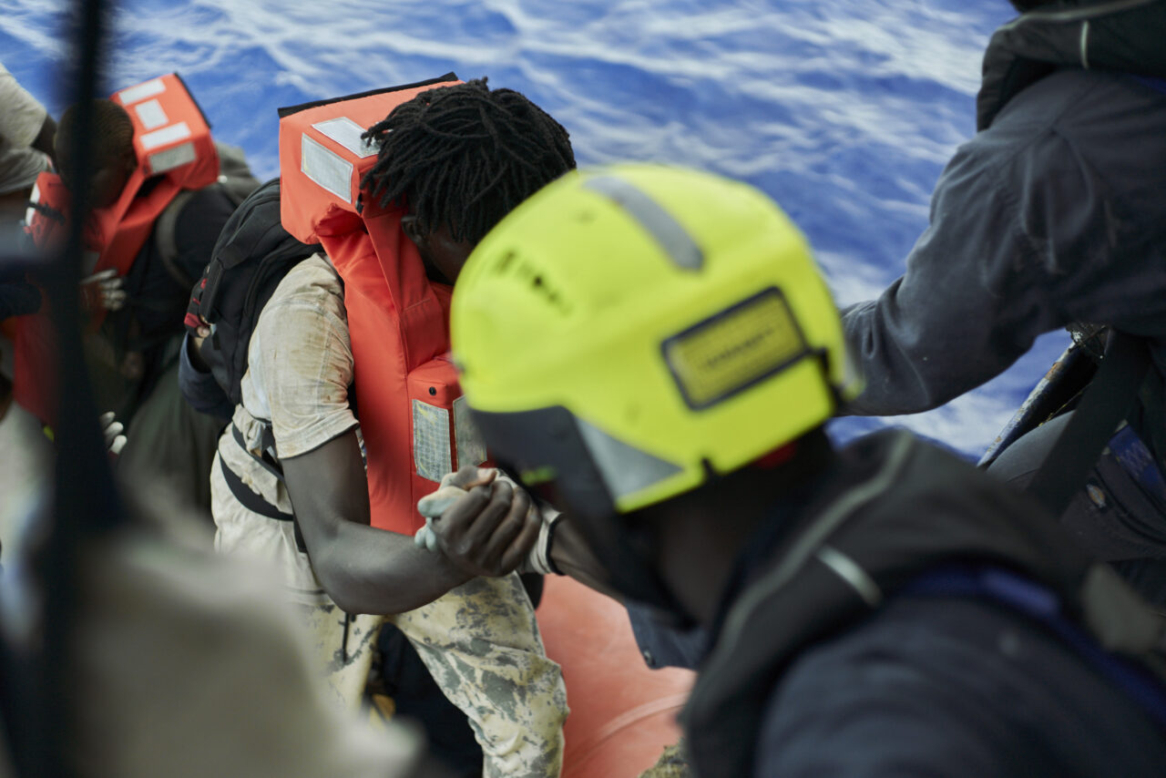 RHIB-Crewmitglied hilft Überlebenden aufs Schnellboot