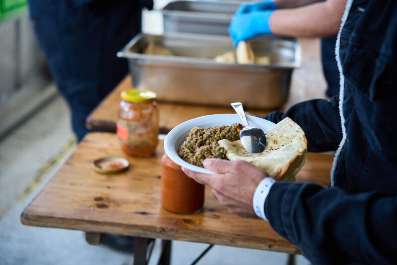 Eine Person an Bord der Humanity 1 hält einen Teller mit Essen in der Hand.