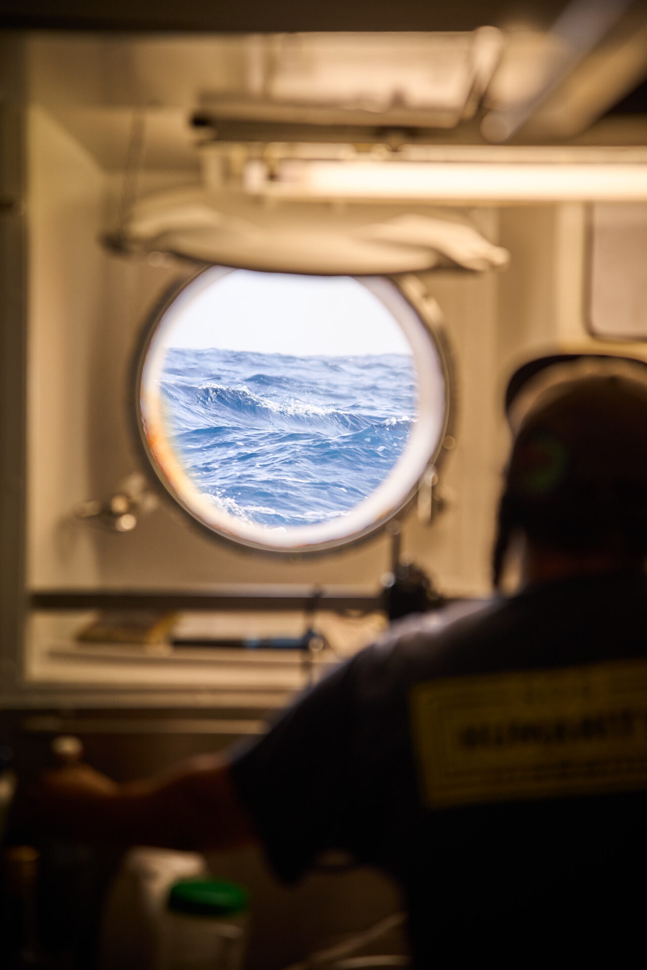 Crew member looking out of a small window on Humanity 1.