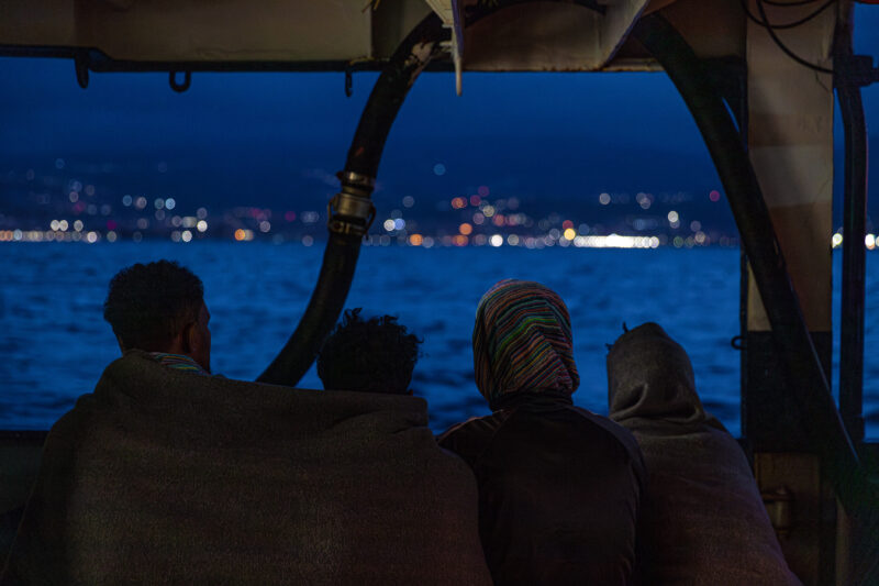 Four people on board the HUmanity 1 looking to the near shore of Italy.
