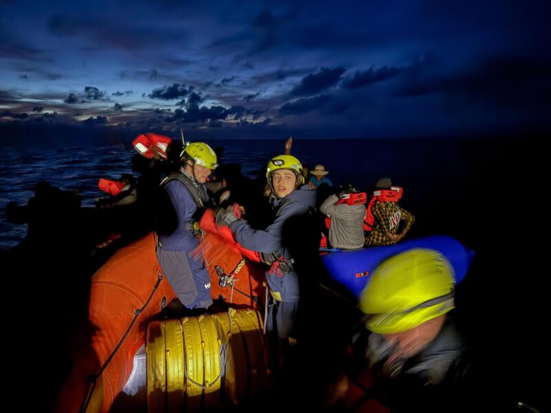 Zwei Crewmitglieder an Bord eines Schnellbootes von SOS Humanity retten mehrere Flüchtlinge aus dem Mittelmeer.